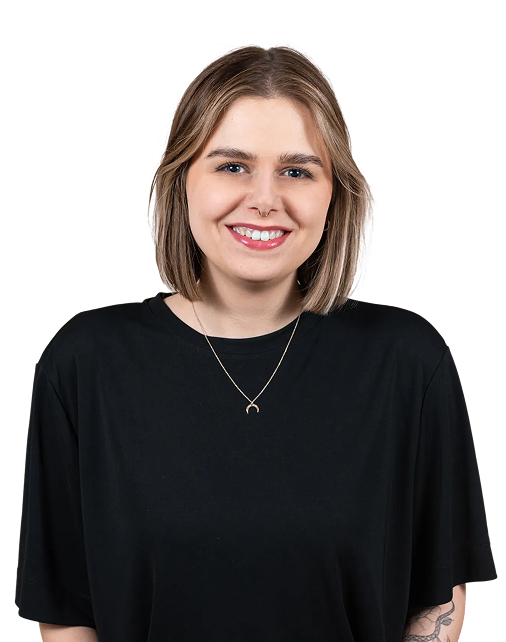 Zdjęcie przedstawia Agnieszkę Rapacz z zespołu MTA Digital. Agnieszka stoi na wprost aparatu, uśmiecha się, ma jasnobrązowe włosy do ramion i nosi czarną bluzkę oraz delikatny naszyjnik. Na jej lewym przedramieniu widoczny jest tatuaż. Tło zostało wycięte – postać umieszczona jest na przezroczystym tle, co nadaje zdjęciu nowoczesny, profesjonalny charakter.