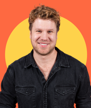 Smiling man with curly blonde hair wearing a dark denim shirt against an orange and yellow background.