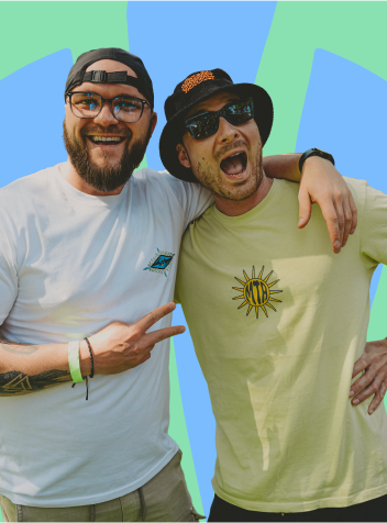 Two smiling men pose outdoors; one wears glasses and a white shirt, the other wears a bucket hat and sunglasses.