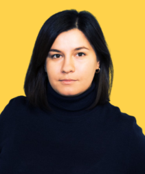 Portret młodej kobiety z ciemnymi włosami, ubranej w granatowy golf, na jednolitym żółtym tle.