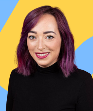 Smiling woman with shoulder-length purple hair wearing a black turtleneck against a yellow and blue abstract background.