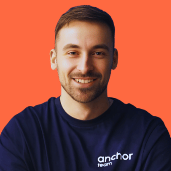 Grafika przedstawia portret Mateusza Szajkowskiego na jednolitym, intensywnie pomarańczowym tle. Postać znajduje się na środku kadru, patrzy bezpośrednio w obiektyw i uśmiecha się w naturalny, przyjazny sposób. Ma krótkie włosy oraz lekki zarost. Ubrany jest w granatową bluzę z widocznym logo „anchor team”, co nadaje całości swobodny, nowoczesny charakter. Proste tło i centralna kompozycja skupiają uwagę na osobie, budując wizerunek otwarty i profesjonalny.