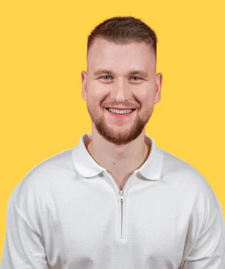 Young, smiling man with short hair and a beard, wearing a white polo shirt against a bright yellow background.