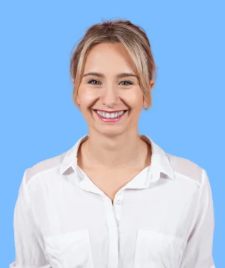 Smiling blonde woman wearing a white shirt, against a solid light blue background.