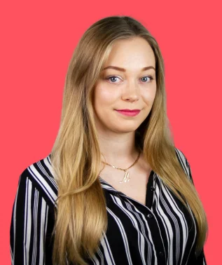 Young woman with long blonde hair wearing a black-and-white striped shirt, against a bright pink background.