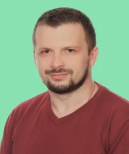 Portrait of a man with short hair and a beard, wearing a burgundy top, against a light turquoise background.