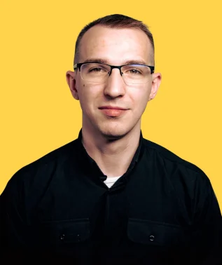 Young man wearing glasses and a black shirt, against a bright yellow background.