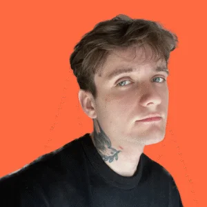 Young man with brown hair and blue eyes, wearing a black sweatshirt, with a bird tattoo on his neck, against an orange background.