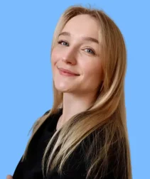 Young woman with light hair and blue eyes, smiling against a light blue background.