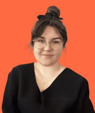 Young woman wearing glasses and a black top, with her hair pulled up in a bun, against an orange background.